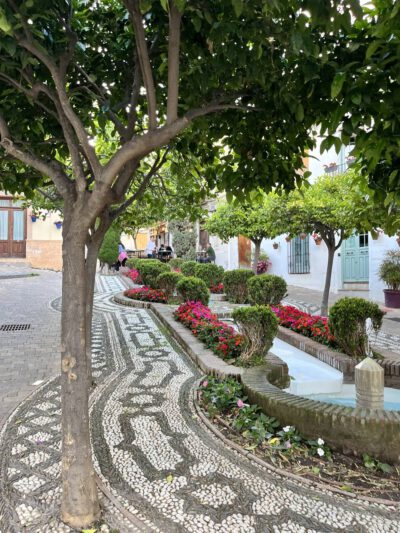 Vakantie woning Estepona old town omgeving, straatje met fontein, bloemen, bomen en oude gebouwen.
