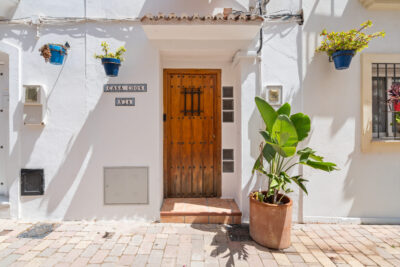 Vakantiewoning Estepona oude centrum, houten voordeur met plant en bloempotten aan de muur.