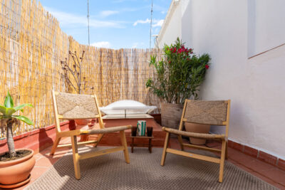 Vakantiewoning Estepona prive dakterras met loungegedeelte, rieten stoelen, jutte kleed en planten.